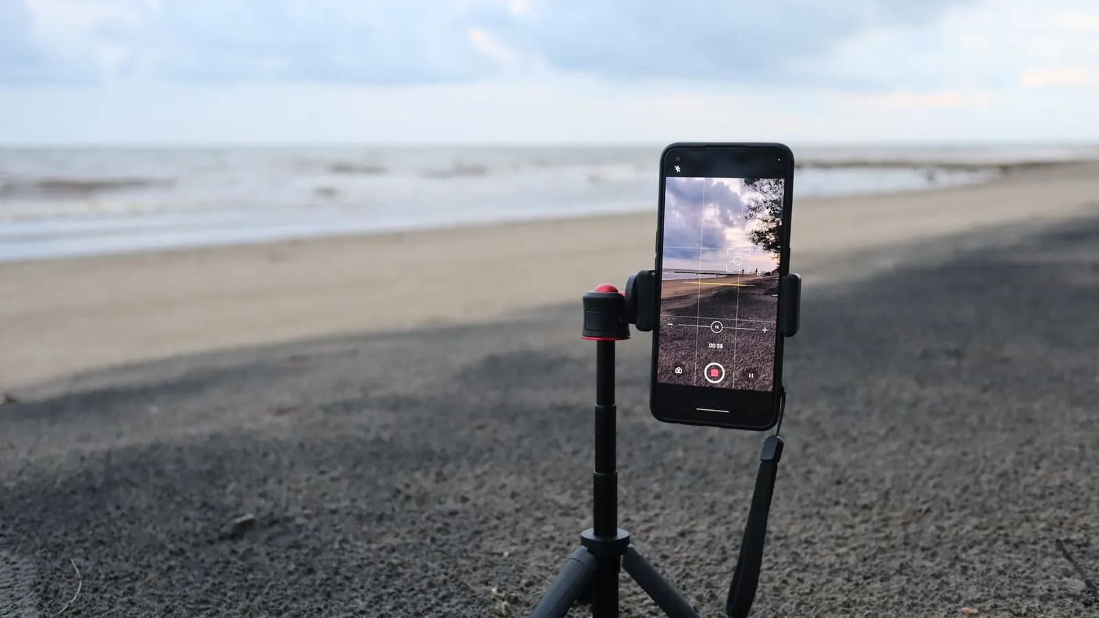 Ponsel dalam posisi vertikal terpasang di tripod untuk merekam video