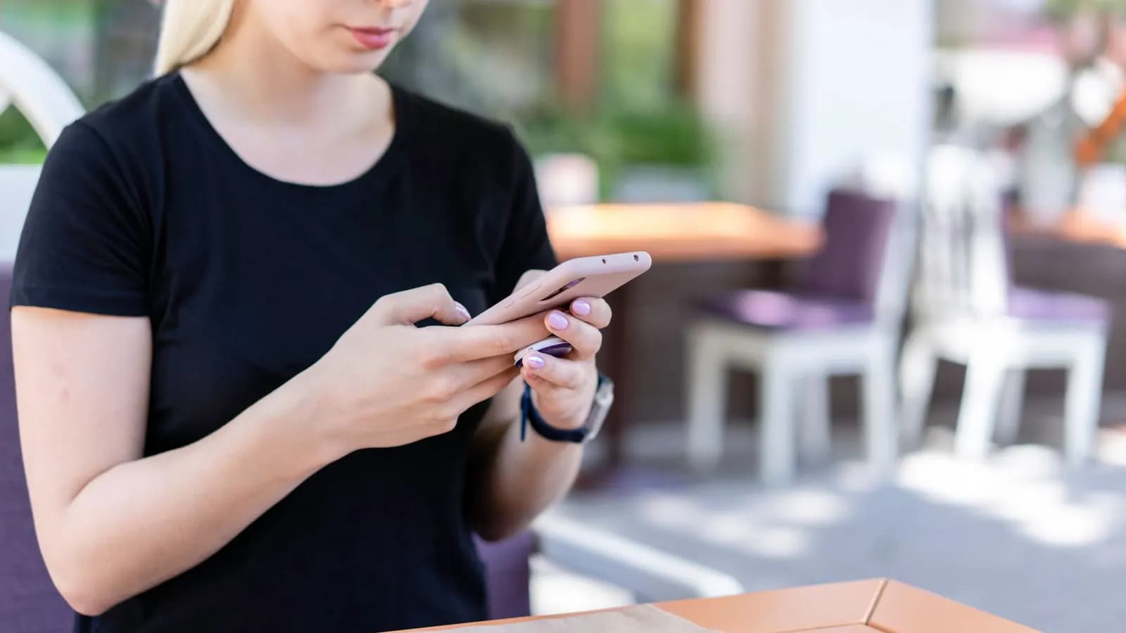 Seseorang memegang ponsel di meja kafe