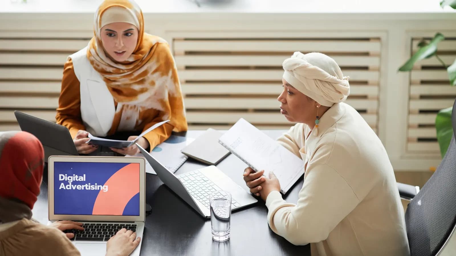 Tim kecil merencanakan materi iklan di depan laptop dan catatan