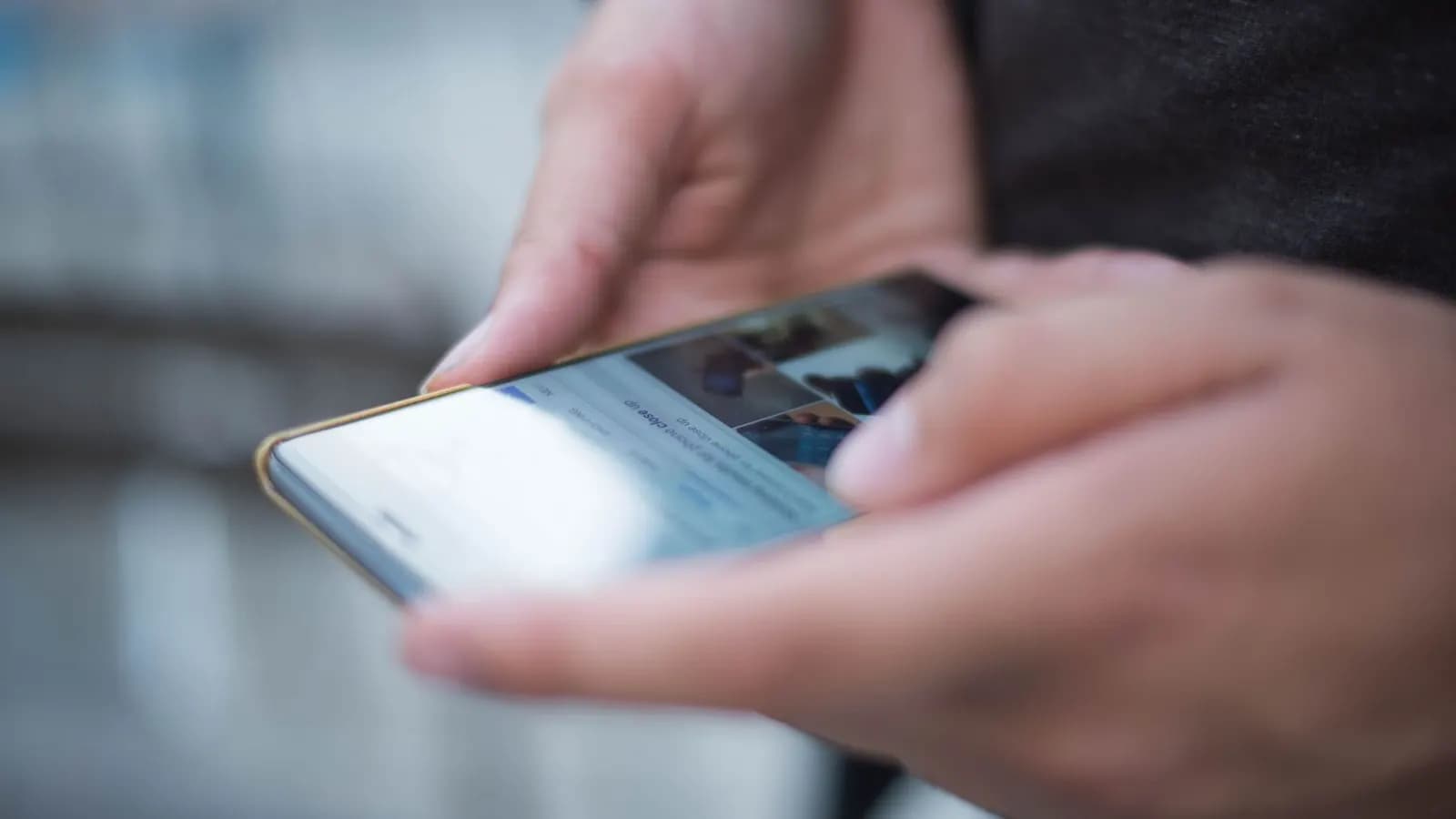 Tangan memegang ponsel sambil menggulir aplikasi media sosial