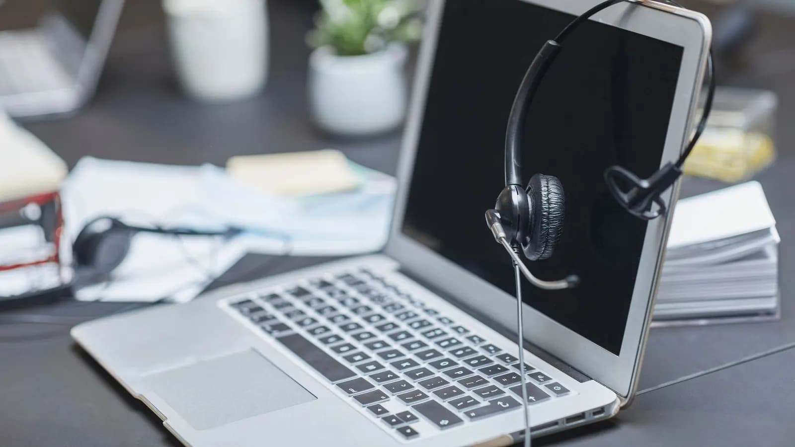 Headphone di samping laptop di atas meja kerja